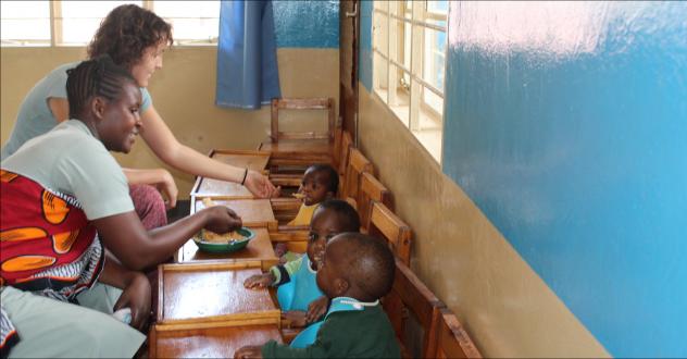 Freiwilligeneinsatz im Ausland: Anna Siegmund und Tarisila Kayombo füttern Jaqueline, Ayubu und Ema mit Brei aus Ugali, Ei und Tomate im Kinderhaus des lutherischen Krankenhauses in Ilembula (Tansania).