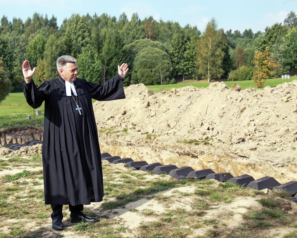 Pfarrer Michael Schwarzkopf steht neben Pappsärgen auf einem Soldaten- friedhof bei St. Petersburg. 525 deutsche Wehr- machtssoldaten, deren Gebeine in den letzten drei Jahren im Nord- westen Russlands geborgen wurden, finden hier ihre letzte Ruhestätte. © picture alliance/Andre Ballin