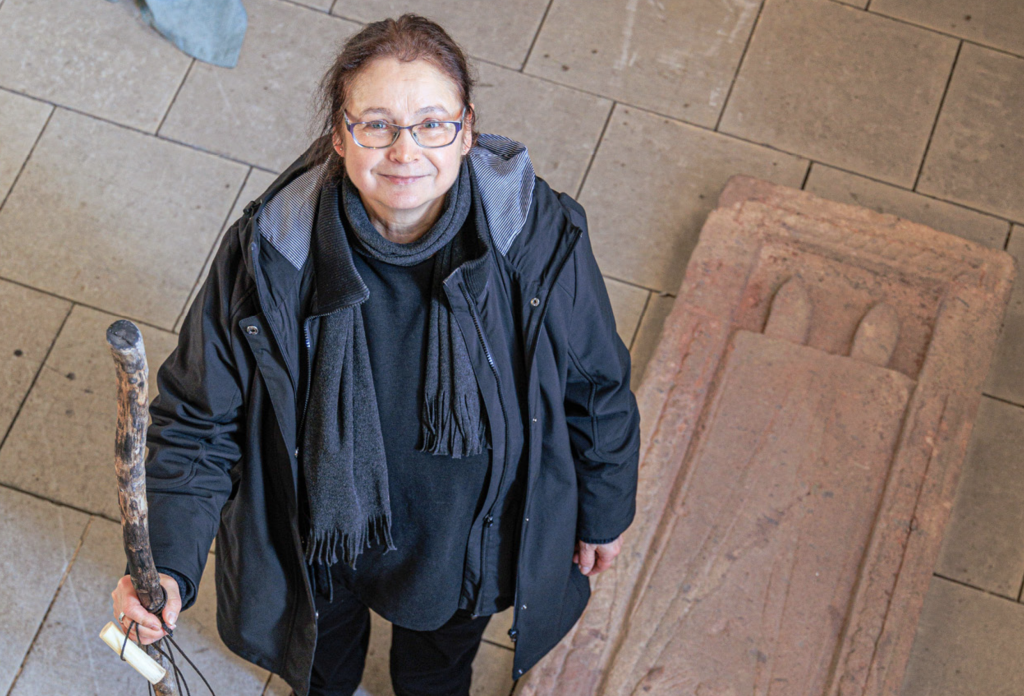 Pfarrerin Birgit Silberbach steht mit Wanderstock am Judithstein in der Kirche Trebsen. Zu ihrer neuen Pfarrstelle gehört die Pilgerarbeit. © Uwe Winkler