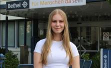 Für Bethel im Internet: Anna Hofmann vor den von Bodelschwinghschen Stiftungen. Auf dem Instagram-Kanal @1jahr_menschennah schreibt die 18-Jährige Beiträge über die diakonische Arbeit. © epd-bild/Katrin Nordwald